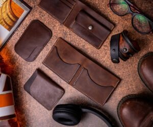 Brown leather wallets and cardholders, boots, headphones, flat lay from above with copy space. Businessman accessories stylish clothes