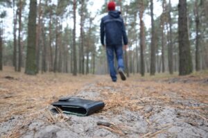 Young man loses his purse with euro money bills on Russian autumn fir wood path. Carelessness and losing wallet concept